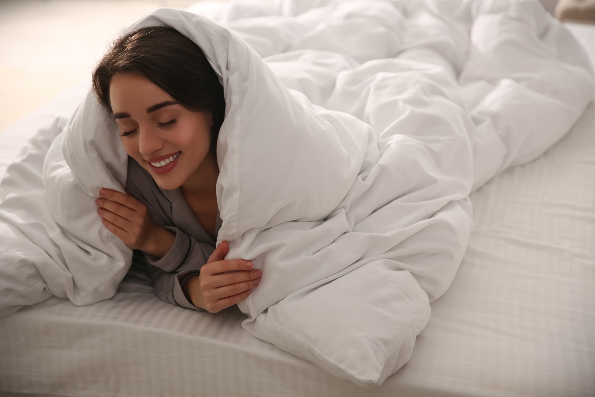 Mulher deitada em sua cama com edredom Mulher deitada em sua cama com edredom